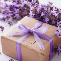 Gift box of premium lavender body care products with a purple ribbon surrounded by lavender flowers on a light background by House of Agave.
