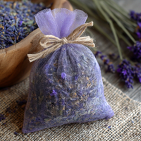 Sachet of dried lavender buds tied with twine on a rustic background with lavender flowers surrounding the sachet.