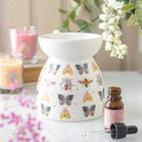 Aromatherapy diffuser with butterfly design on a table with candles and flowers.