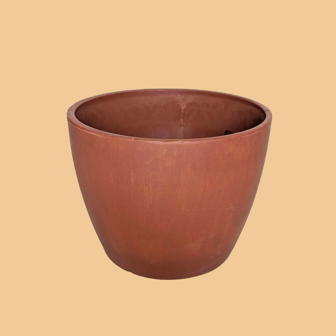 Terracotta-colored planter on a green background from House of Agave.