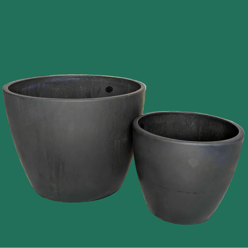 Two black plant pots for houseplants against a green background.